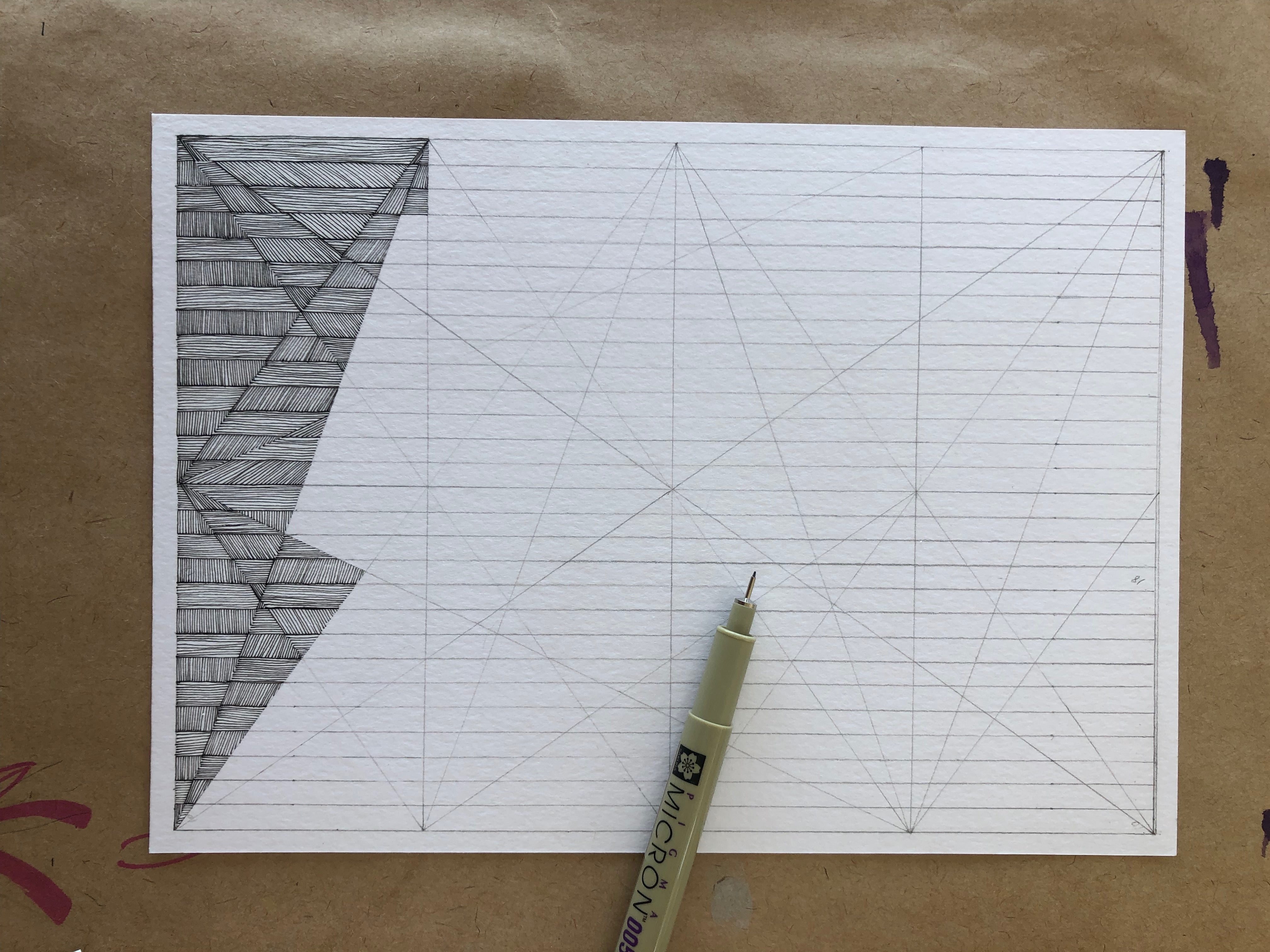Black ink geometric drawing in progress on grid paper, showing angular shaded patterns on the left side with precise linework. A Sakura Pigma Micron archival pen rests on the paper, capturing the artist's work mid-creation on a kraft paper surface.
